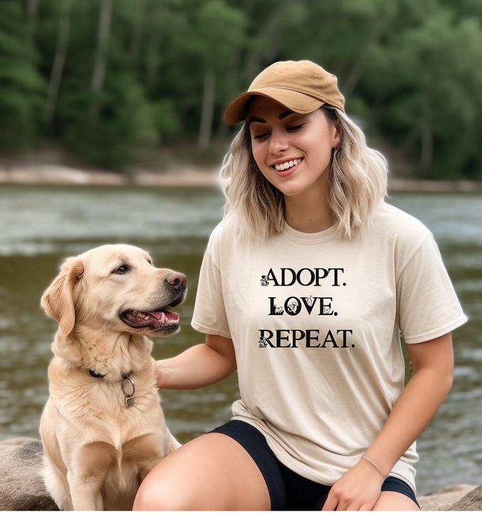Adopt. Love. Repeat. T-shirt featuring bold black text with small puppy and kitten accents incorporated into the letters. Printed on a soft, ivory unisex tee, this design is perfect for pet lovers, rescue advocates, and animal adoption supporters. Ideal for wearing to adoption events, volunteering at shelters, or showing pride in giving animals a forever home.