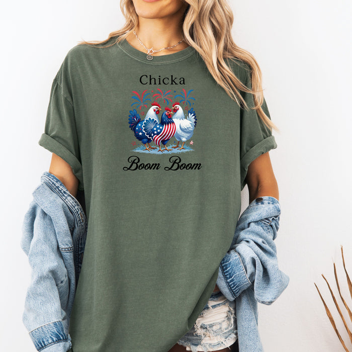 Moss t-shirt featuring a playful 'Chicka Boom Boom' design with three patriotic chickens, one decorated in red, white, and blue stars and stripes, and the other in white, surrounded by colorful fireworks. A third chicken is decorated in red and white stars on a blue body. A fun and festive shirt perfect for 4th of July, barbecues, summer parties, and casual patriotic celebrations.