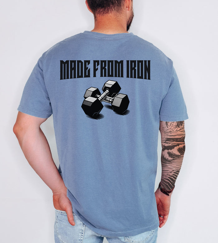 Person wearing a blue jean T-shirt with a bold back design that reads “Made From Iron” in strong, block lettering above an illustration of two black dumbbells. The graphic captures a powerful, fitness-inspired aesthetic, perfect for gym enthusiasts, weightlifters, and strength training fans who want to showcase their dedication and passion for lifting.