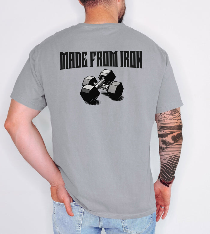 Person wearing a grey T-shirt with a bold back design that reads “Made From Iron” in strong, block lettering above an illustration of two black dumbbells. The graphic captures a powerful, fitness-inspired aesthetic, perfect for gym enthusiasts, weightlifters, and strength training fans who want to showcase their dedication and passion for lifting.