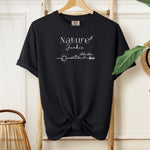 Nature Junkie T-shirt with minimalist white line art showing a sun, mountains, trees, and the words 'Nature Junkie Adventure' with a small leaf accent. Printed on a soft black unisex Comfort Colors tee, perfect for outdoor lovers, hikers, campers, and those who enjoy exploring nature and adventure.