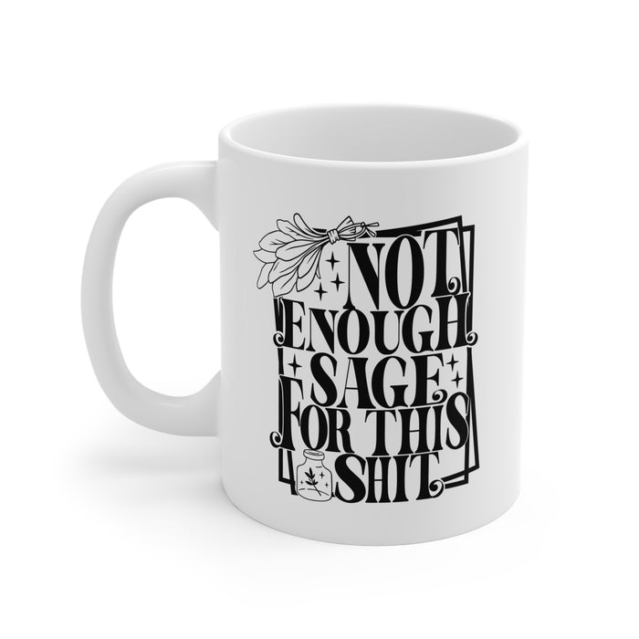 White ceramic mug featuring bold black typography reading “Not Enough Sage For This Shit,” framed in a whimsical outlined border. The design includes a detailed sage bundle illustration at the top and a small jar with a sage leaf motif at the bottom, adding a witchy, mystical vibe. Perfect for humorous coffee or tea moments, it blends sassy attitude with boho and spiritual flair, making it an ideal gift for friends with a sense of humor.
