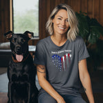 A person wearing a pepper T-shirt featuring a heart-shaped design made of dripping red, white, and blue paw prints with star accents. Above the heart, the text reads “Paws & Stripes Furever,” blending patriotic pride with a love for pets, making it a perfect shirt for animal lovers and USA enthusiasts.