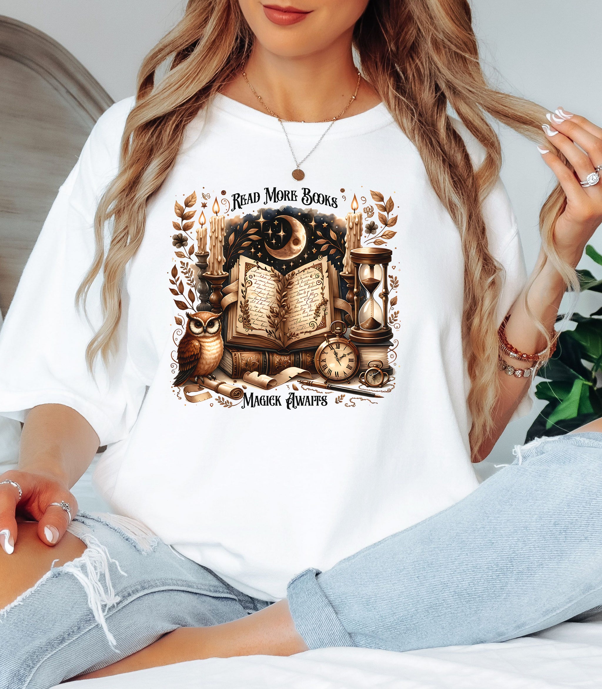Person wearing an white t-shirt featuring a whimsical "Read More Books, Magick Awaits" design. The graphic showcases an open enchanted book surrounded by candles, a crescent moon, owl, pocket watch, hourglass, and magical elements, creating a mystical and literary aesthetic perfect for book lovers and fantasy fans.