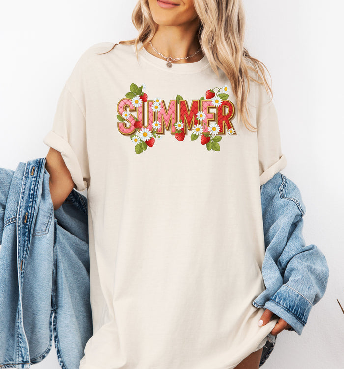 Ivory T-shirt featuring a vibrant “SUMMER” graphic decorated with red strawberries, green leaves, and white daisies. The fresh, playful design captures a bright and cheerful summer vibe, perfect for casual warm-weather outfits.
