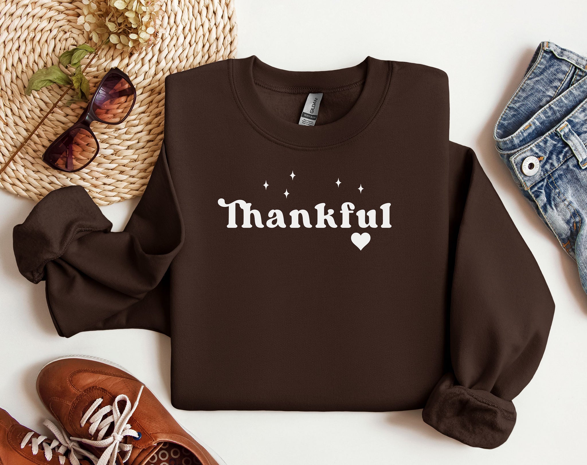Dark Chocolate Gildan sweatshirt featuring the word “Thankful” in bold white retro-style font, accented with small sparkling stars above and a heart below. A simple yet meaningful design that celebrates gratitude and cozy fall vibes—perfect for Thanksgiving, autumn gatherings, or everyday wear.