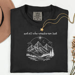 Not All Who Wander Are Lost T-shirt featuring an artistic nature scene with hand-drawn mountains, pine trees, a winding trail, and a starry sky with a crescent moon. This adventurous design, printed on a soft, black comfortable unisex tee, inspires exploration, travel, and a free-spirited lifestyle. Perfect for hikers, nature lovers, and wanderers who embrace the journey and find peace in the great outdoors.