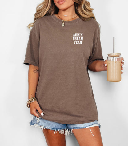 Person wearing an Espresso t-shirt, featuring a minimalist white text design on the left chest that reads "ADMIN DREAM TEAM." Perfect for school staff, office teams, or administrative professionals showing team spirit in a stylish and understated way.
