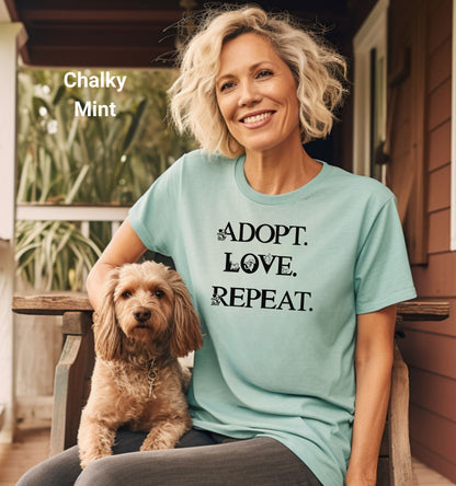 Adopt. Love. Repeat. T-shirt featuring bold black text with small puppy and kitten accents incorporated into the letters. Printed on a soft, chalky mint unisex tee, this design is perfect for pet lovers, rescue advocates, and animal adoption supporters. Ideal for wearing to adoption events, volunteering at shelters, or showing pride in giving animals a forever home.