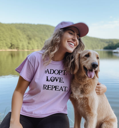 Adopt. Love. Repeat. T-shirt featuring bold black text with small puppy and kitten accents incorporated into the letters. Printed on a soft, violet unisex tee, this design is perfect for pet lovers, rescue advocates, and animal adoption supporters. Ideal for wearing to adoption events, volunteering at shelters, or showing pride in giving animals a forever home.