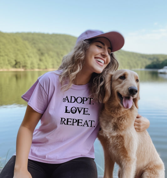 Adopt. Love. Repeat. T-shirt featuring bold black text with small puppy and kitten accents incorporated into the letters. Printed on a soft, violet unisex tee, this design is perfect for pet lovers, rescue advocates, and animal adoption supporters. Ideal for wearing to adoption events, volunteering at shelters, or showing pride in giving animals a forever home.