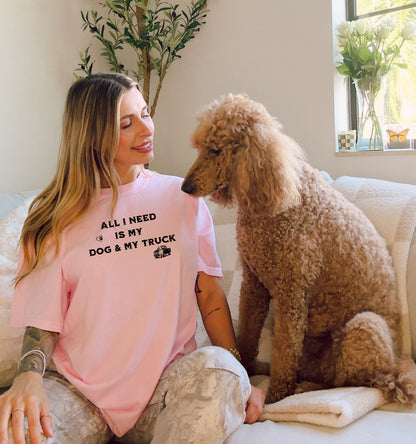 All I Need is My Dog & My Truck T-shirt featuring bold black text with small graphic icons of a paw print heart and a pickup truck. Printed on a blossom pink unisex tee, this casual design is perfect for dog lovers and truck enthusiasts who embrace a laid-back, country lifestyle. Ideal for everyday wear, gifting, or showing off two favorite passions—dogs and trucks.