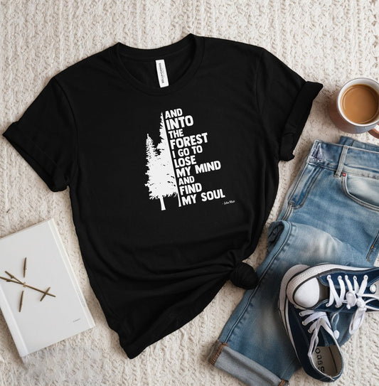 And Into The Forest I Go To Lose My Mind And Find My Soul T-shirt featuring a minimalist nature-inspired design with a tall pine tree alongside bold text of the famous John Muir quote. Printed on a soft black unisex tee, this design celebrates mindfulness, outdoor adventure, and the healing power of nature. Perfect for hikers, campers, and forest lovers who find peace and clarity in the wilderness.