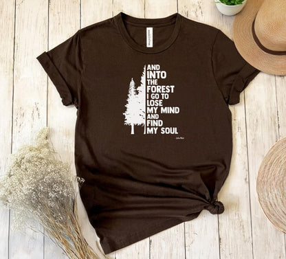 And Into The Forest I Go To Lose My Mind And Find My Soul T-shirt featuring a minimalist nature-inspired design with a tall pine tree alongside bold text of the famous John Muir quote. Printed on a soft brown unisex tee, this design celebrates mindfulness, outdoor adventure, and the healing power of nature. Perfect for hikers, campers, and forest lovers who find peace and clarity in the wilderness.