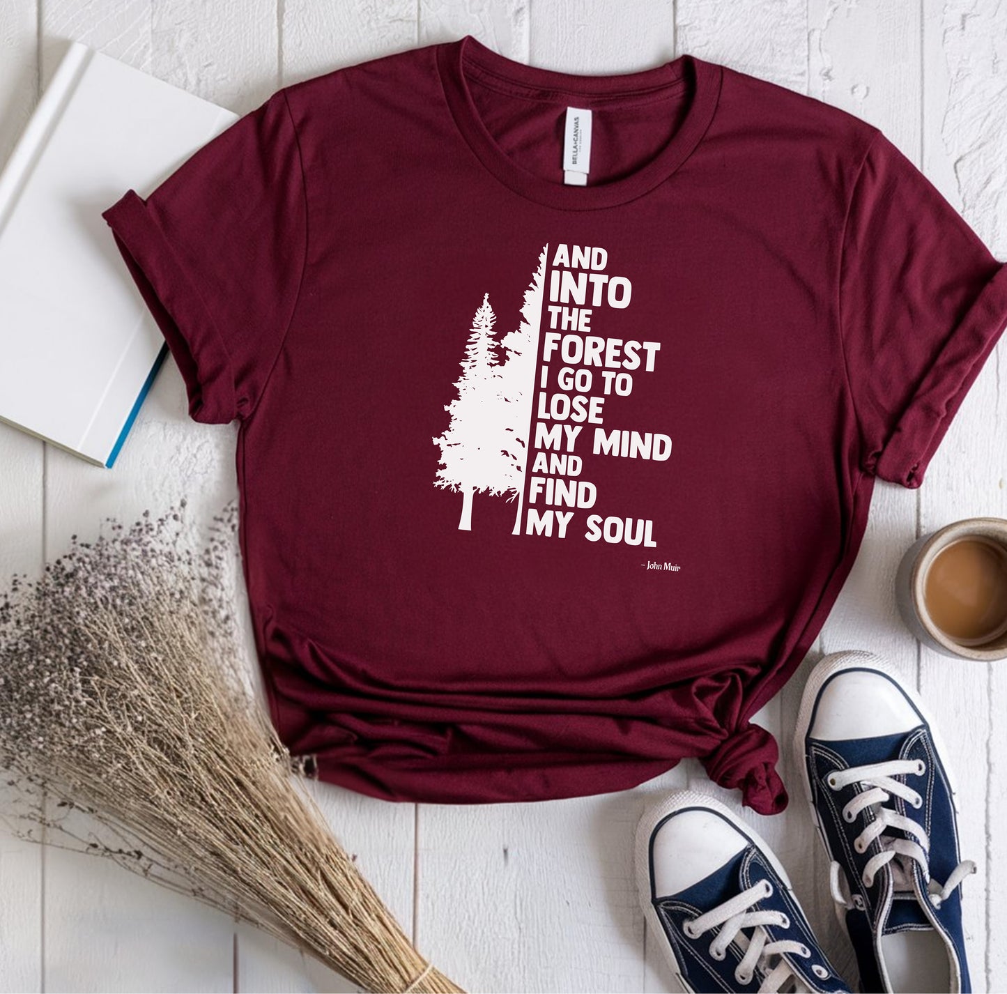 And Into The Forest I Go To Lose My Mind And Find My Soul T-shirt featuring a minimalist nature-inspired design with a tall pine tree alongside bold text of the famous John Muir quote. Printed on a soft maroon unisex tee, this design celebrates mindfulness, outdoor adventure, and the healing power of nature. Perfect for hikers, campers, and forest lovers who find peace and clarity in the wilderness.