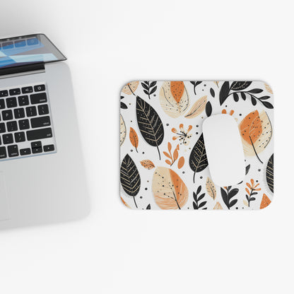 A modern autumn leaves mouse pad with a mouse sitting on it, next to a laptop.