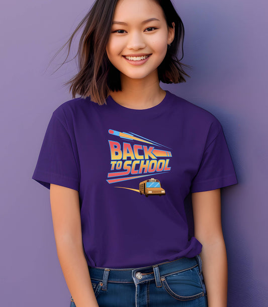 Youth wearing a Team Purple t-shirt with a bold “Back to School” design featuring retro-style typography, a large pencil graphic above the text, and a yellow school bus driving below. A fun and colorful tee perfect for celebrating the new school year with energy and excitement.