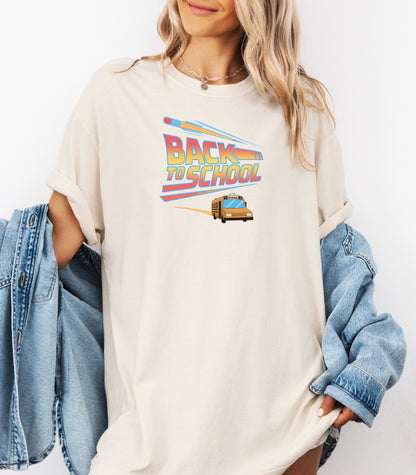 Person wearing a an Ivory t-shirt with a bold “Back to School” design featuring retro-style typography, a large pencil graphic above the text, and a yellow school bus driving below. A fun and colorful tee perfect for celebrating the new school year with energy and excitement.