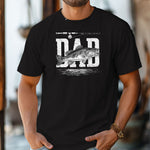 Dad Bass Fishing T-shirt featuring the word 'DAD' in bold, distressed white lettering with a detailed bass fish illustration overlaying the text. A fishing rod graphic runs above the design, with subtle water ripple details below. Printed on a black unisex tee, this shirt is perfect for dads who love fishing, making it an ideal gift for Father’s Day, birthdays, or weekend fishing trips.