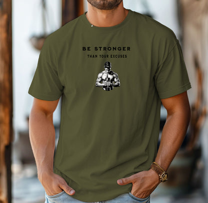 Person wearing a hemp color T-shirt featuring the motivational phrase “Be Stronger Than Your Excuses” in bold black lettering, with a graphic of a muscular figure holding a dumbbell below the text. Perfect for gym-goers, fitness enthusiasts, and athletes, this empowering workout shirt inspires determination, discipline, and strength training focus.