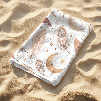 A white beach towel featuring a boho-style design with earthy-toned feathers, crescent moons, stars, and celestial accents neatly folded and laying on the sand. Set against a sunny ocean backdrop, this mystical and artistic towel brings dreamy, free-spirited vibes—perfect for beach days, festivals, or mindful relaxation.