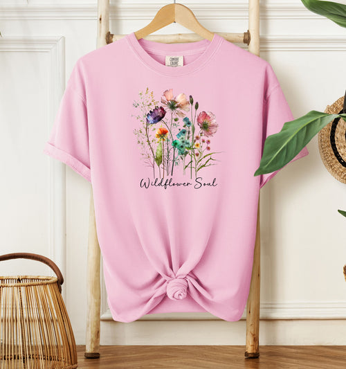 Wildflower Soul T-shirt featuring a soft watercolor-style bouquet of colorful wildflowers with delicate stems and leaves. Printed on a blossom pink unisex Comfort Colors tee, this nature-inspired boho design is perfect for free spirits, gardeners, flower lovers, and those with a love for the outdoors and artistic floral fashion.