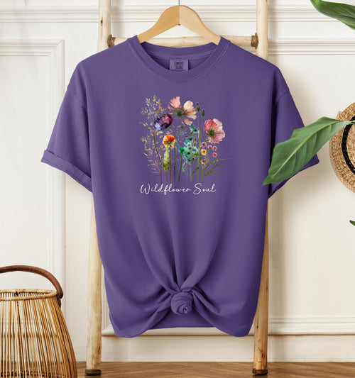 Wildflower Soul T-shirt featuring a soft watercolor-style bouquet of colorful wildflowers with delicate stems and leaves. Printed on a grape unisex Comfort Colors tee, this nature-inspired boho design is perfect for free spirits, gardeners, flower lovers, and those with a love for the outdoors and artistic floral fashion.