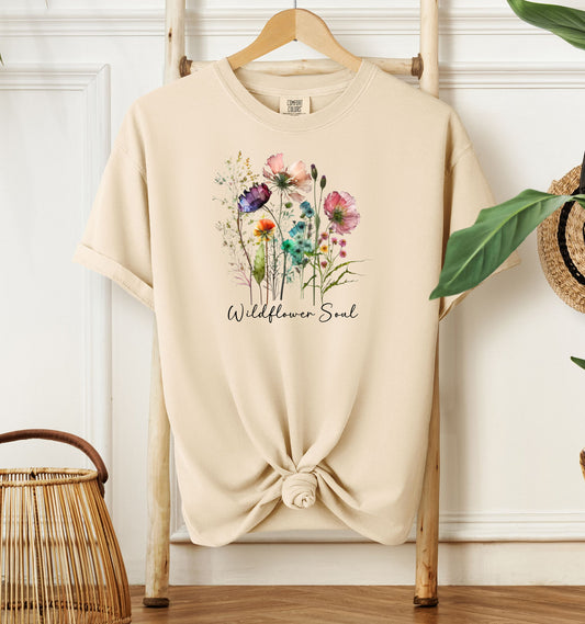 Wildflower Soul T-shirt featuring a soft watercolor-style bouquet of colorful wildflowers with delicate stems and leaves. Printed on an Ivory unisex Comfort Colors tee, this nature-inspired boho design is perfect for free spirits, gardeners, flower lovers, and those with a love for the outdoors and artistic floral fashion.