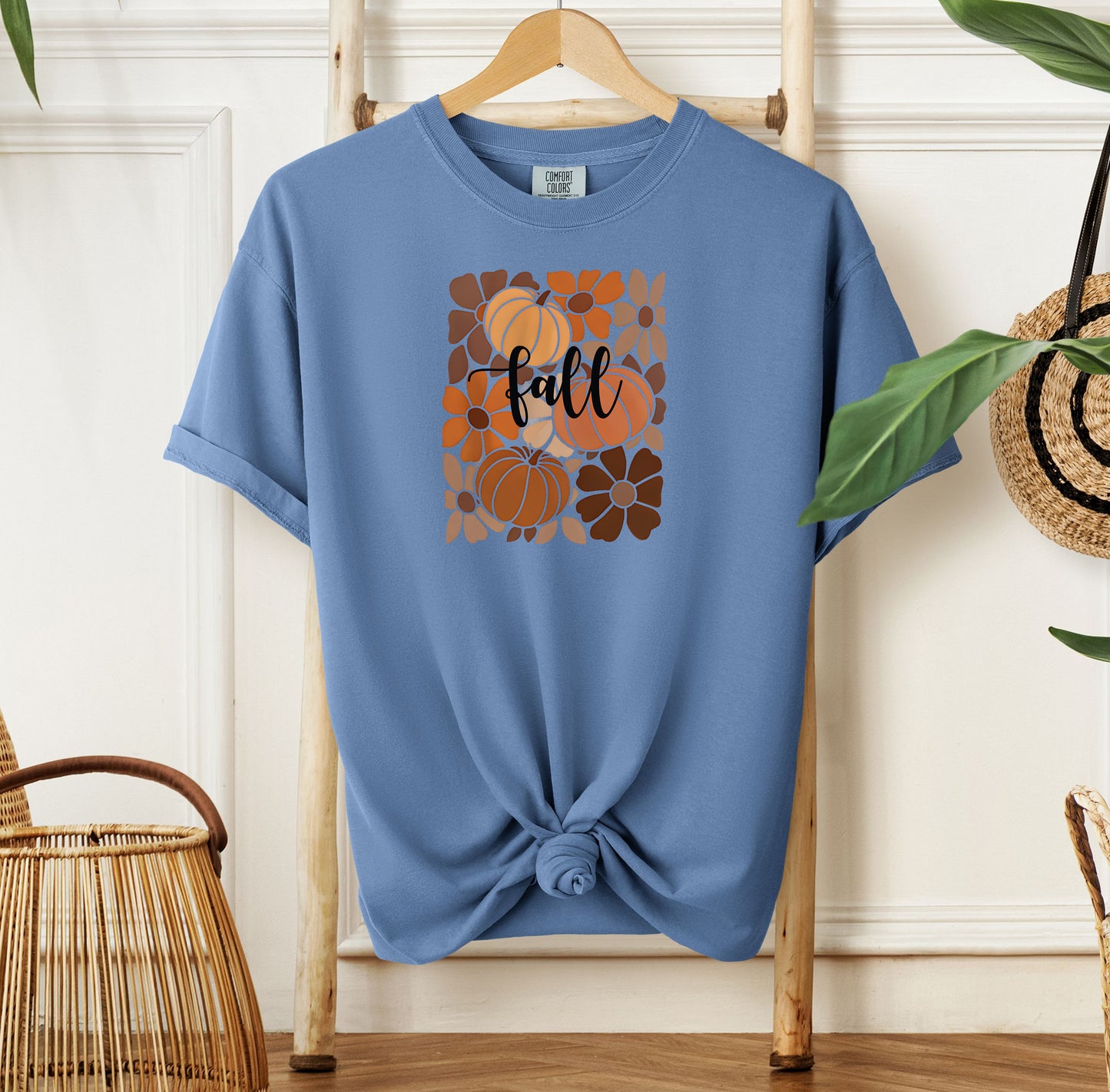 Washed Denim T-shirt featuring a boho-inspired fall design with hand-drawn pumpkins and flowers in warm autumn tones. The word "fall" is written in elegant script across the center of the graphic, framed by a mosaic-style floral and pumpkin pattern. Perfect for seasonal style and cozy autumn vibes.