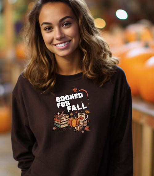 Dark Chocolate Gildan sweatshirt featuring a cozy autumn-themed “Booked For Fall” design with stacked books, pumpkin, coffee mug, scarf, glasses, and falling leaves in warm fall tones. Perfect for book lovers who embrace sweater weather, pumpkin spice, and cozy reading sessions during the autumn season.