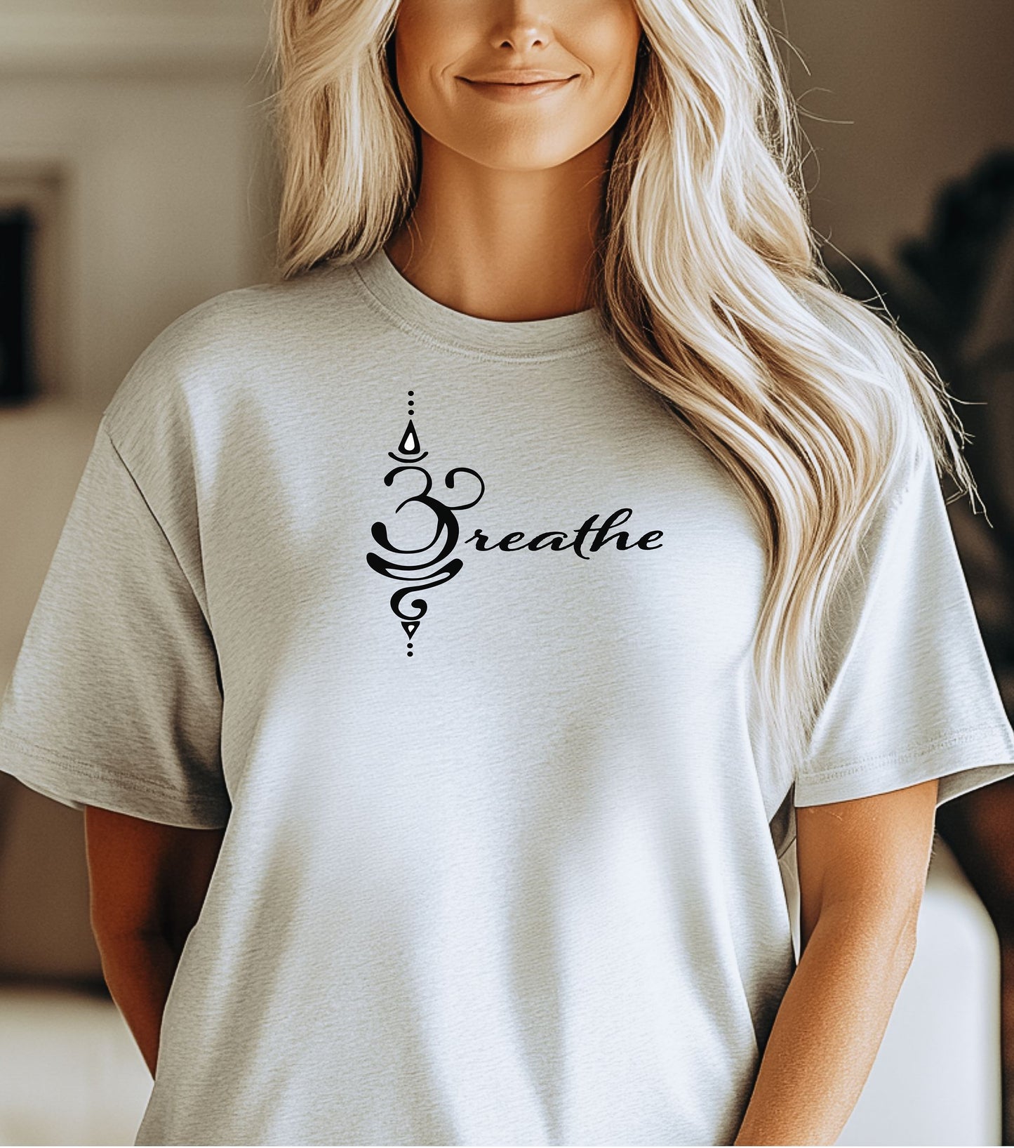 Breathe in Sanskrit T-shirt featuring an elegant black Sanskrit-inspired symbol integrated with the word 'Breathe' in flowing script. Printed on a soft, short-sleeve ash unisex tee, this calming design promotes mindfulness and relaxation. Perfect for yoga enthusiasts, meditation practitioners, and anyone embracing a peaceful, intentional lifestyle.