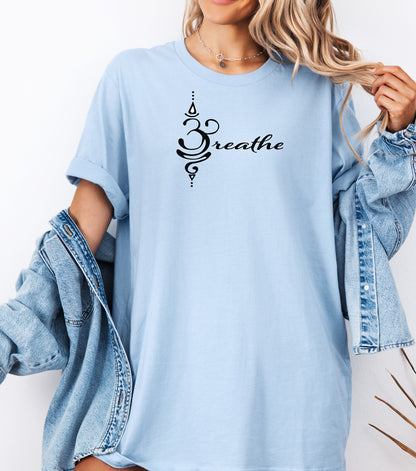 Breathe in Sanskrit T-shirt featuring an elegant black Sanskrit-inspired symbol integrated with the word 'Breathe' in flowing script. Printed on a soft, short-sleeve chambray light blue unisex tee, this calming design promotes mindfulness and relaxation. Perfect for yoga enthusiasts, meditation practitioners, and anyone embracing a peaceful, intentional lifestyle.
