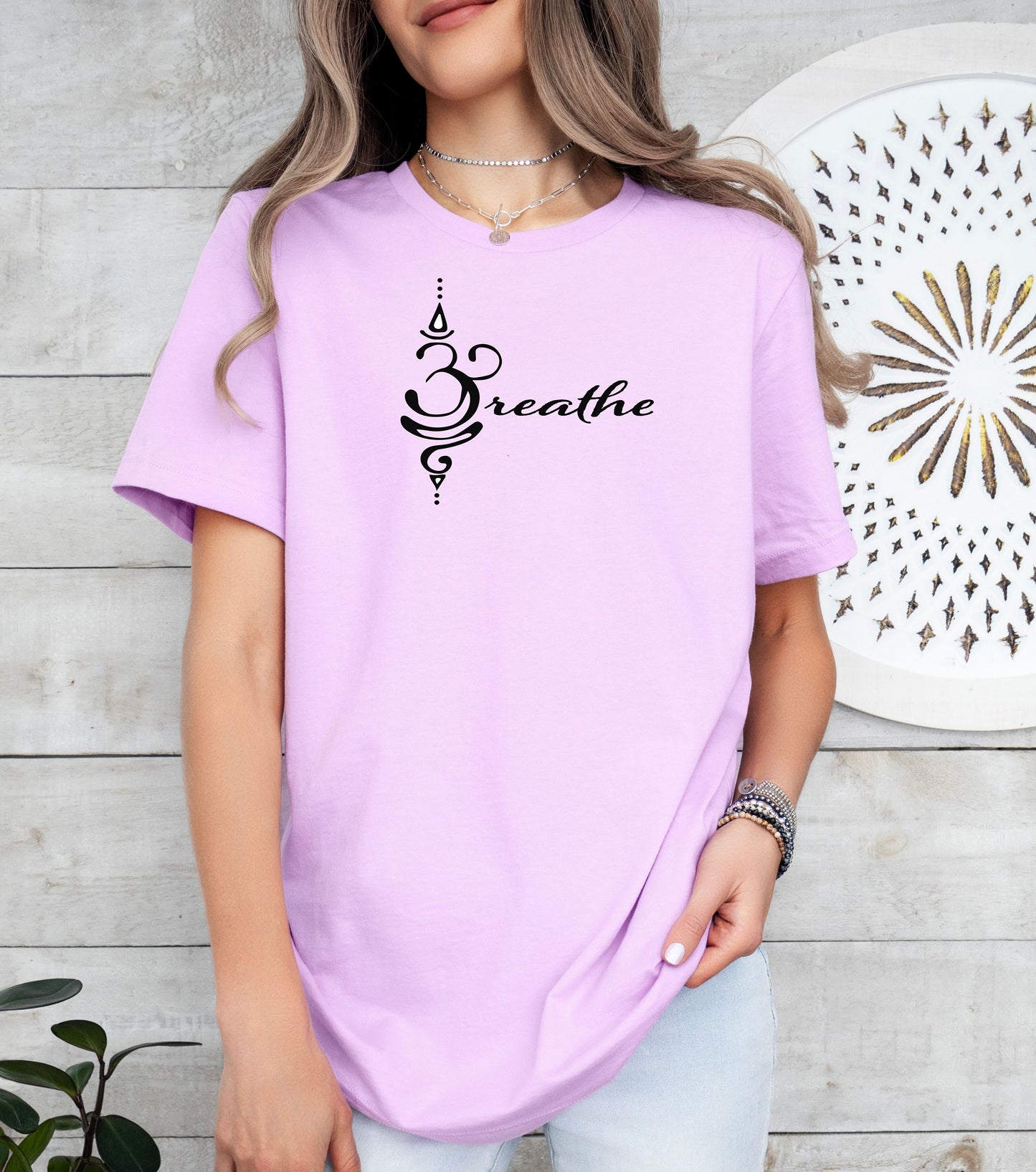 Breathe in Sanskrit T-shirt featuring an elegant black Sanskrit-inspired symbol integrated with the word 'Breathe' in flowing script. Printed on a soft, short-sleeve lilac unisex tee, this calming design promotes mindfulness and relaxation. Perfect for yoga enthusiasts, meditation practitioners, and anyone embracing a peaceful, intentional lifestyle.