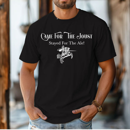 Man wearing a black T-shirt with a fun Renaissance Faire design that reads “Came For The Joust, Stayed For The Ale!” in medieval-style font. The graphic features a white illustration of a jousting knight on horseback with lance raised, capturing the festive spirit of jousting tournaments and hearty faire revelry.