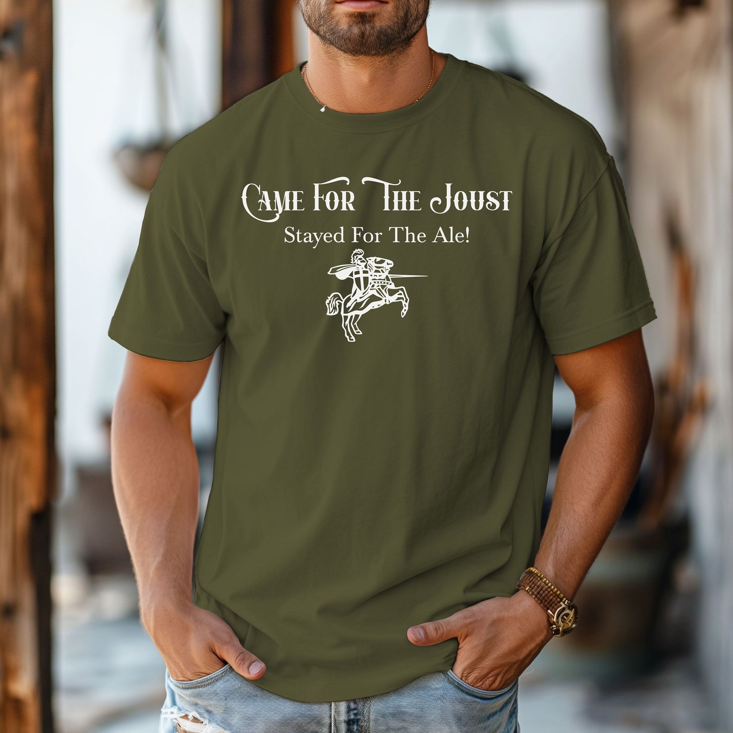 Man wearing a Hemp color T-shirt with a fun Renaissance Faire design that reads “Came For The Joust, Stayed For The Ale!” in medieval-style font. The graphic features a white illustration of a jousting knight on horseback with lance raised, capturing the festive spirit of jousting tournaments and hearty faire revelry.