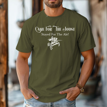 Man wearing a Hemp color T-shirt with a fun Renaissance Faire design that reads “Came For The Joust, Stayed For The Ale!” in medieval-style font. The graphic features a white illustration of a jousting knight on horseback with lance raised, capturing the festive spirit of jousting tournaments and hearty faire revelry.