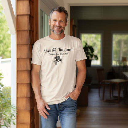 Man wearing an Ivory T-shirt with a fun Renaissance Faire design that reads “Came For The Joust, Stayed For The Ale!” in medieval-style font. The graphic features a white illustration of a jousting knight on horseback with lance raised, capturing the festive spirit of jousting tournaments and hearty faire revelry.