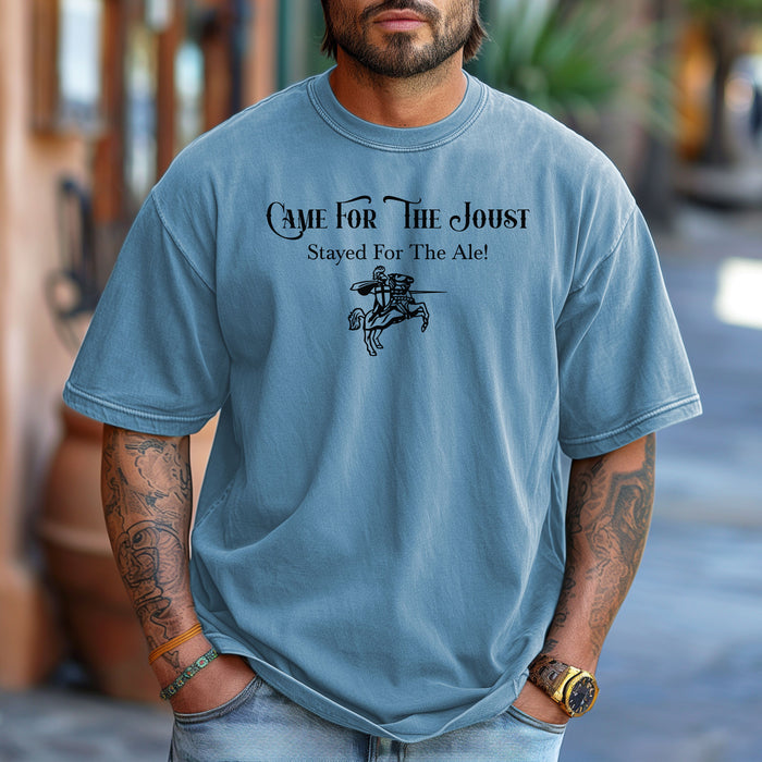Man wearing a Washed Denim T-shirt with a fun Renaissance Faire design that reads “Came For The Joust, Stayed For The Ale!” in medieval-style font. The graphic features a white illustration of a jousting knight on horseback with lance raised, capturing the festive spirit of jousting tournaments and hearty faire revelry.
