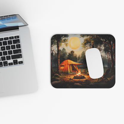 Mouse pad with camping design next to a laptop on a white surface