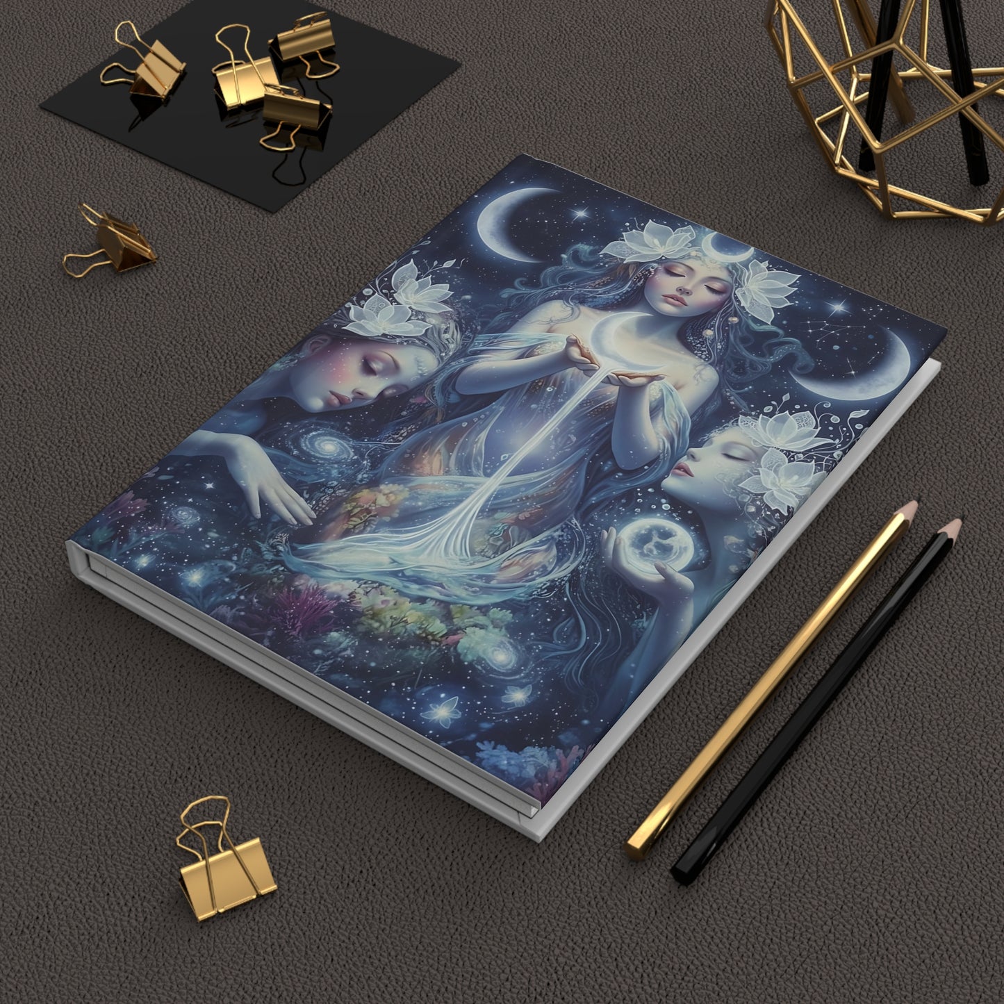 Celestial Lunar Goddesses Journal with artistic cover featuring celestial design on a dark surface with stationery items.