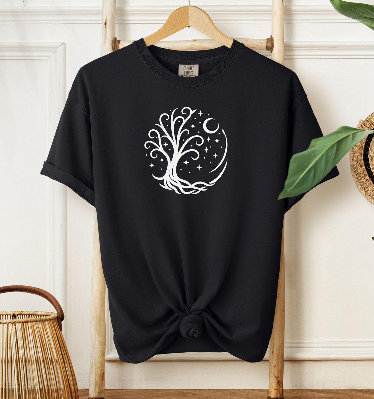 Celestial Tree of Life T-shirt featuring a white mystical tree design within a circular frame of stars, crescent moon, and swirling roots. Printed on a black unisex Comfort Colors tee, this nature-inspired celestial design is perfect for free spirits, stargazers, boho style lovers, and anyone drawn to cosmic, spiritual, or magical themes.
