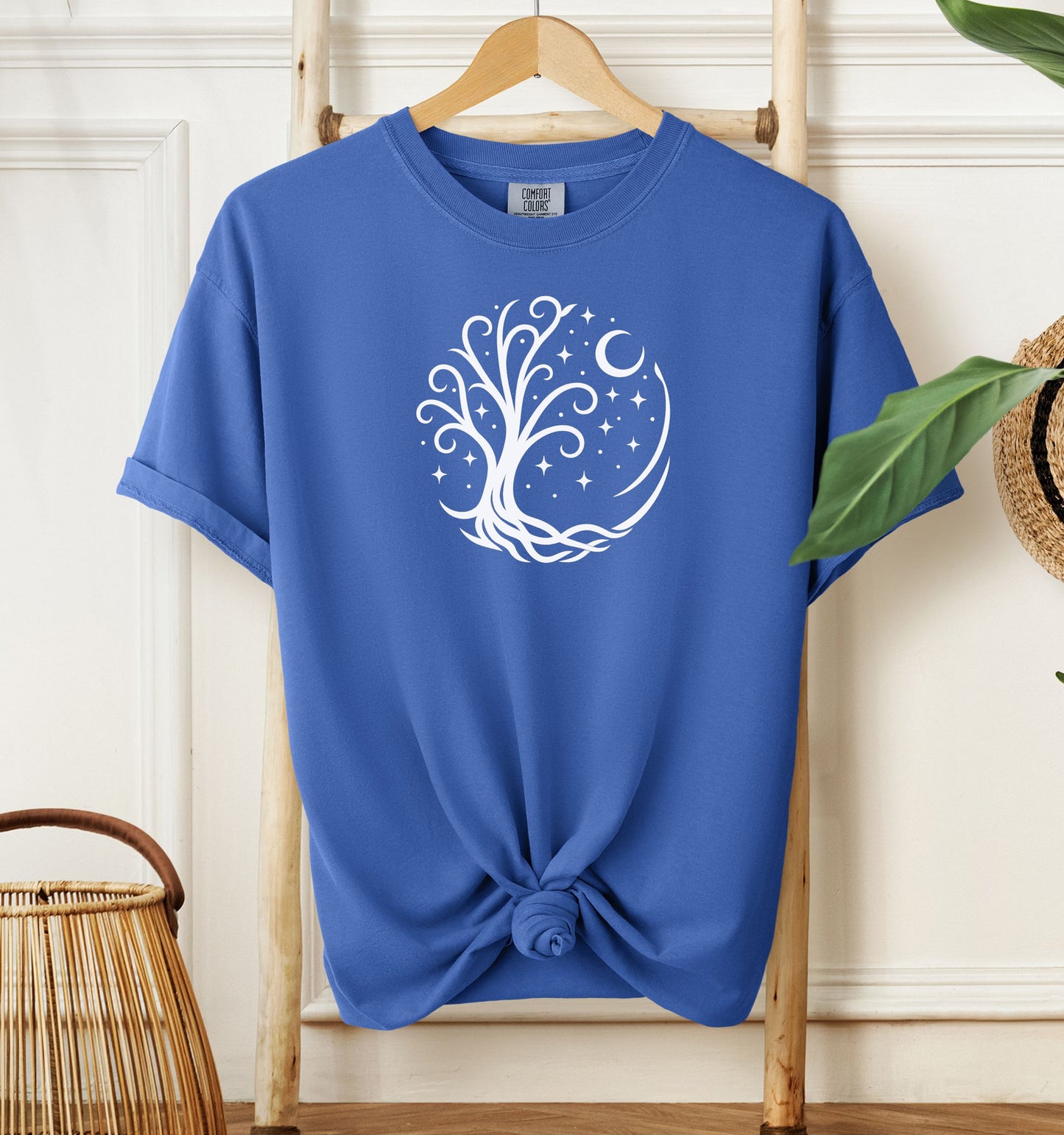Celestial Tree of Life T-shirt featuring a white mystical tree design within a circular frame of stars, crescent moon, and swirling roots. Printed on a mystic blue unisex Comfort Colors tee, this nature-inspired celestial design is perfect for free spirits, stargazers, boho style lovers, and anyone drawn to cosmic, spiritual, or magical themes.