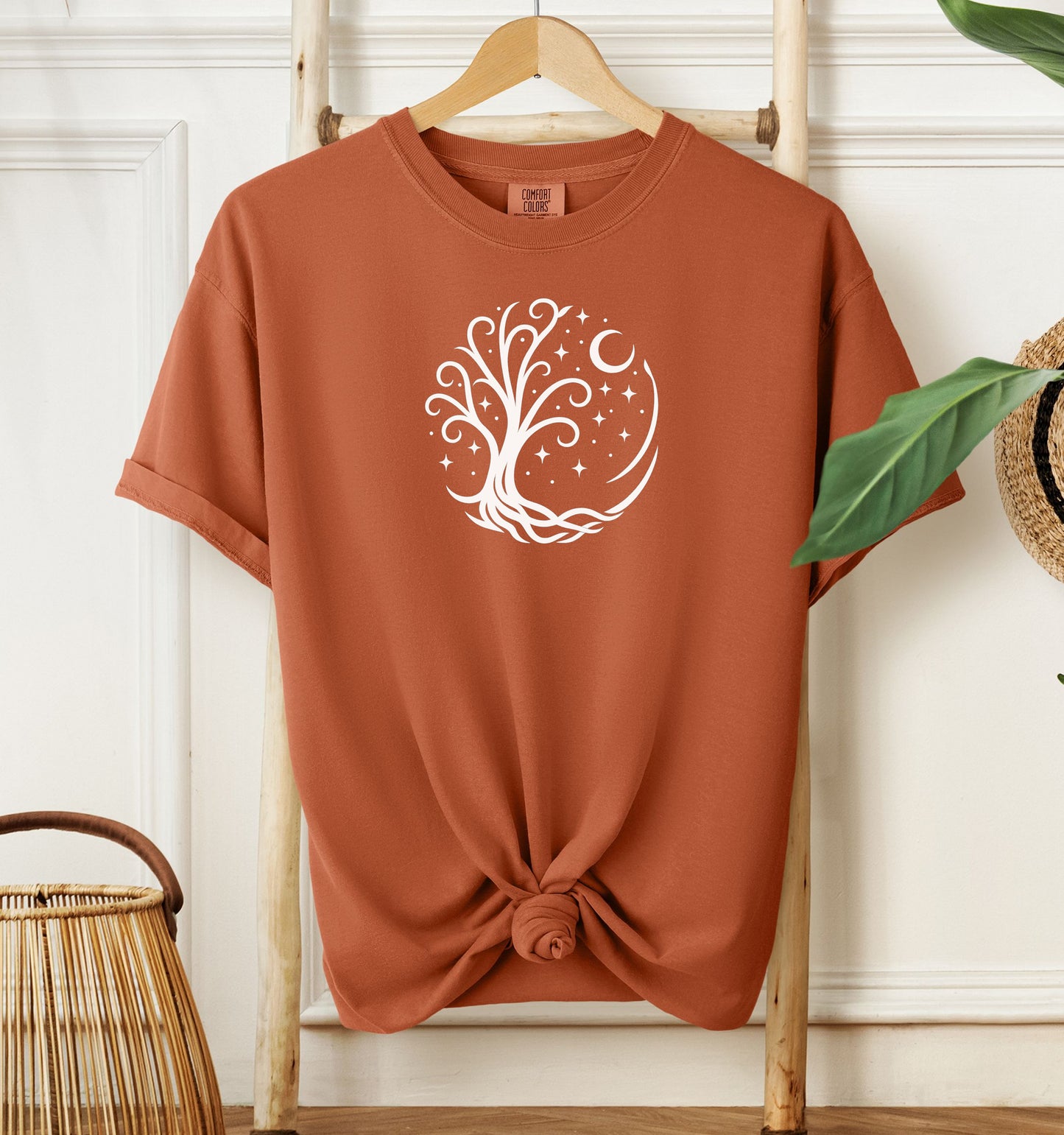 Celestial Tree of Life T-shirt featuring a white mystical tree design within a circular frame of stars, crescent moon, and swirling roots. Printed on a yam unisex Comfort Colors tee, this nature-inspired celestial design is perfect for free spirits, stargazers, boho style lovers, and anyone drawn to cosmic, spiritual, or magical themes.