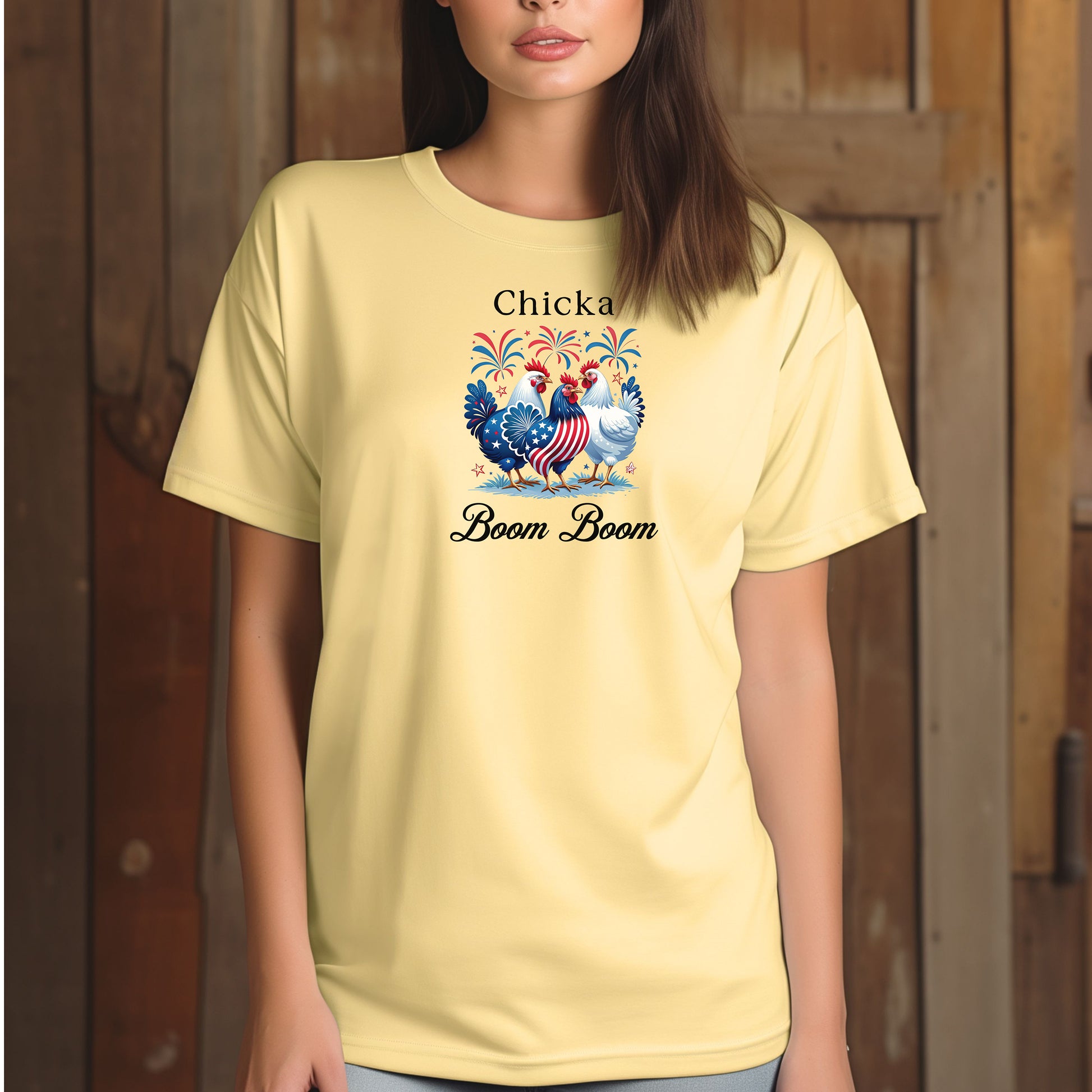 Banana t-shirt featuring a playful 'Chicka Boom Boom' design with three patriotic chickens, one decorated in red, white, and blue stars and stripes, and the other in white, surrounded by colorful fireworks. A third chicken is decorated in red and white stars on a blue body.  A fun and festive shirt perfect for 4th of July, barbecues, summer parties, and casual patriotic celebrations.