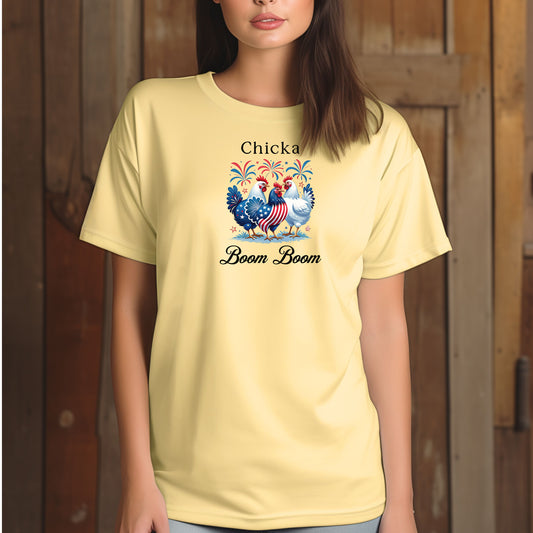 Banana t-shirt featuring a playful 'Chicka Boom Boom' design with three patriotic chickens, one decorated in red, white, and blue stars and stripes, and the other in white, surrounded by colorful fireworks. A third chicken is decorated in red and white stars on a blue body.  A fun and festive shirt perfect for 4th of July, barbecues, summer parties, and casual patriotic celebrations.