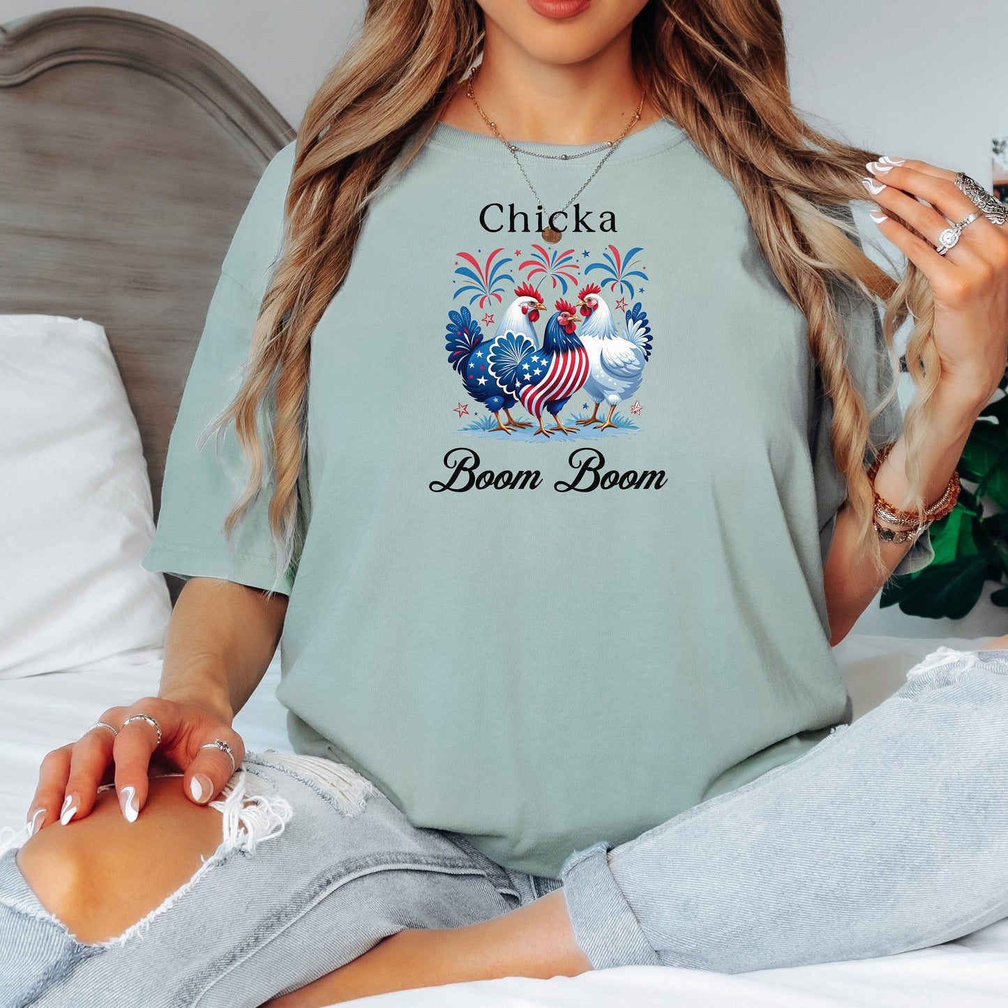 Bay light green t-shirt featuring a playful 'Chicka Boom Boom' design with three patriotic chickens, one decorated in red, white, and blue stars and stripes, and the other in white, surrounded by colorful fireworks. A third chicken is decorated in red and white stars on a blue body.  A fun and festive shirt perfect for 4th of July, barbecues, summer parties, and casual patriotic celebrations.