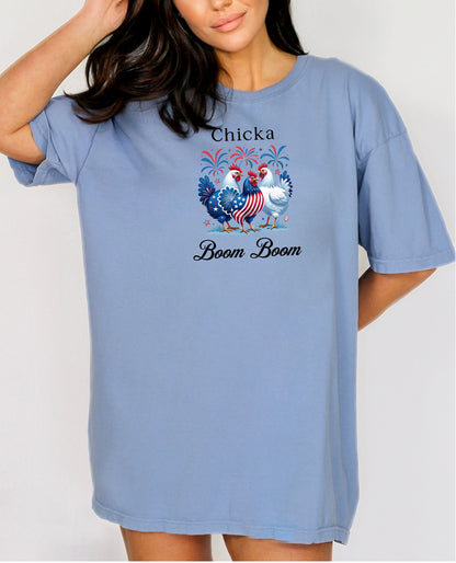 Washed Denim t-shirt featuring a playful 'Chicka Boom Boom' design with three patriotic chickens, one decorated in red, white, and blue stars and stripes, and the other in white, surrounded by colorful fireworks. A third chicken is decorated in red and white stars on a blue body.  A fun and festive shirt perfect for 4th of July, barbecues, summer parties, and casual patriotic celebrations.