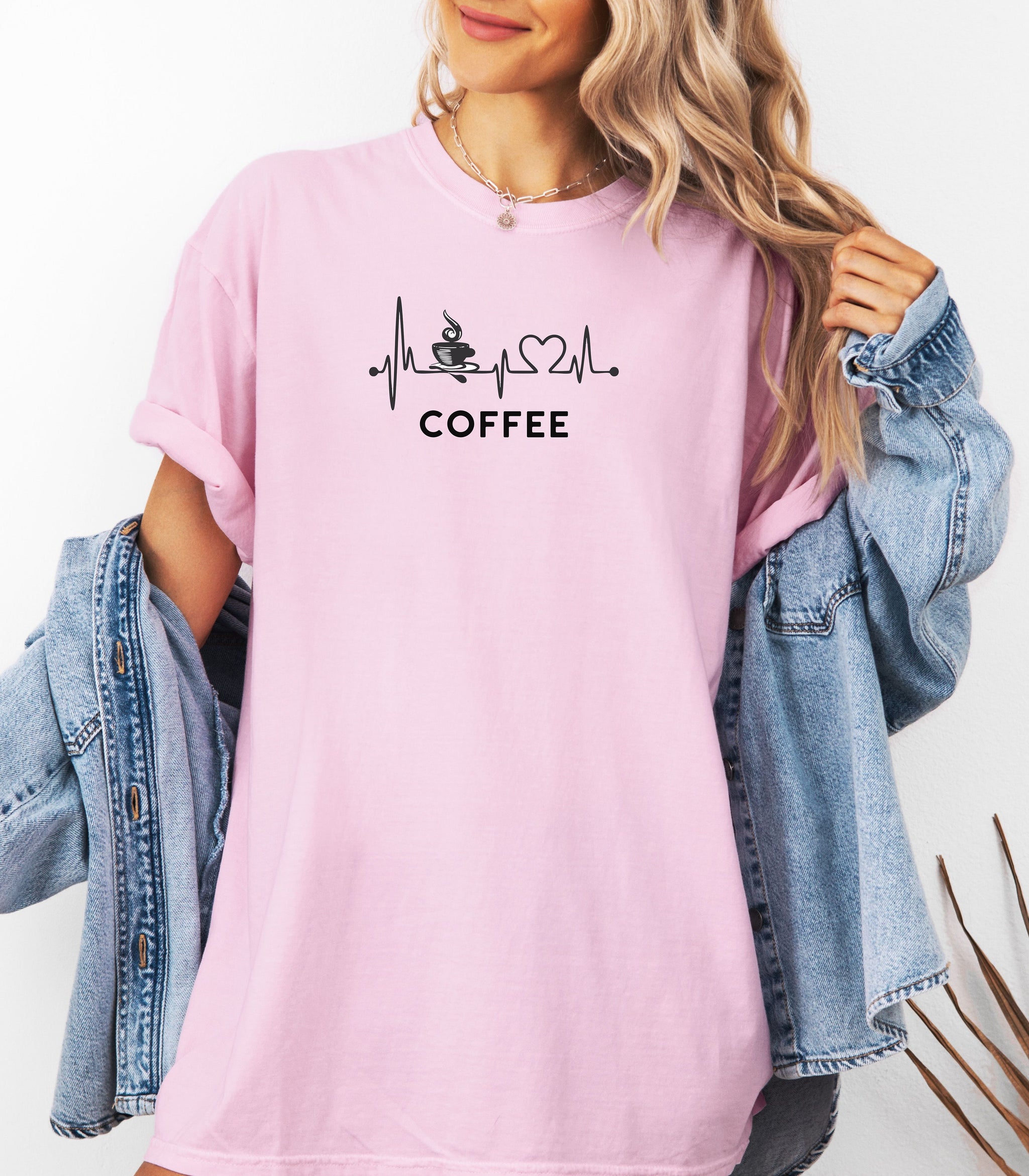 Graphic Blossom pink t-shirt design featuring a heartbeat line that flows through a steaming coffee cup and forms a heart shape before it finishes. A creative and stylish illustration that shows coffee is essential to life—perfect for caffeine lovers, baristas, and anyone whose heart beats for coffee.