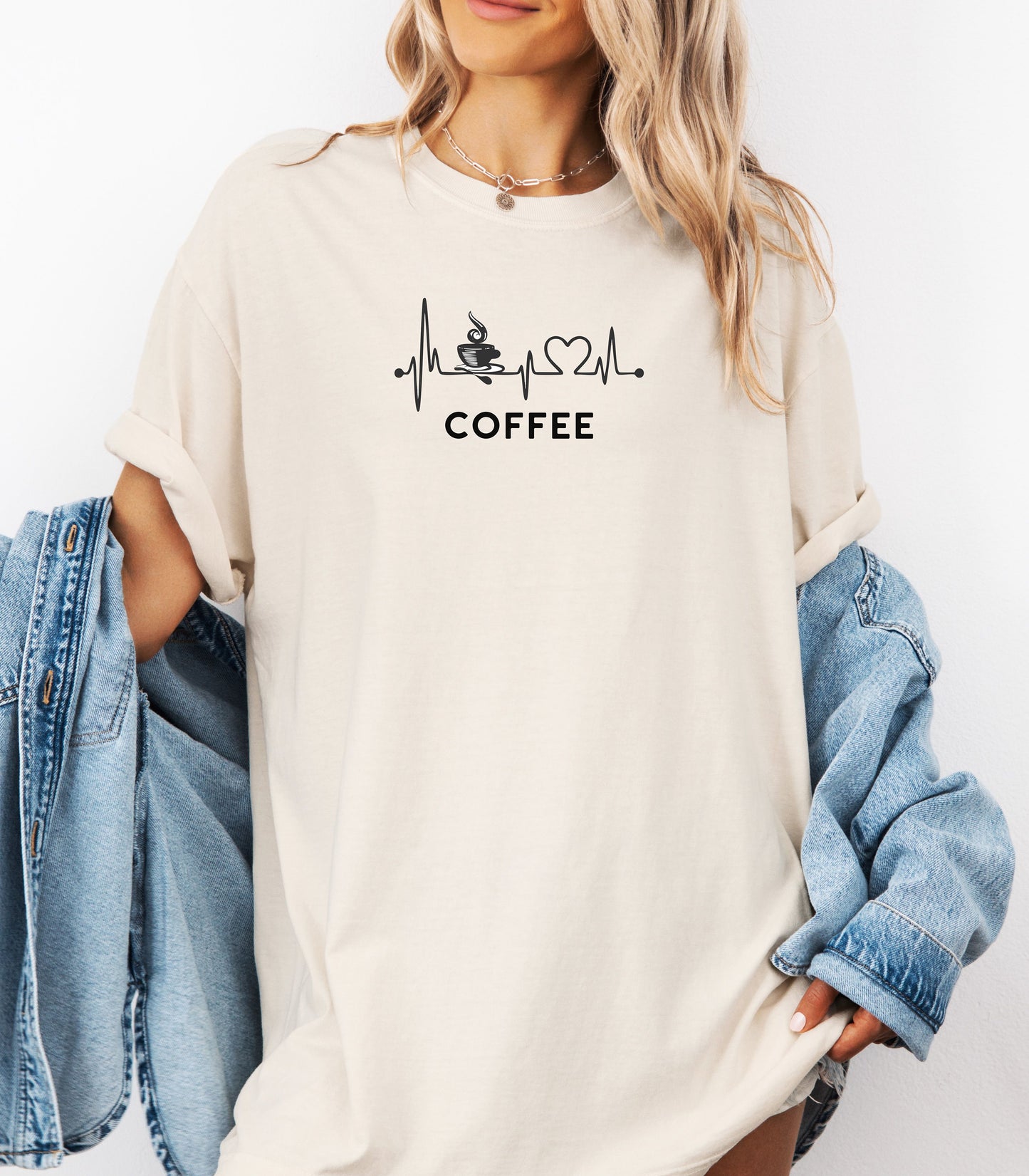 Graphic Ivory t-shirt design featuring a heartbeat line that flows through a steaming coffee cup and forms a heart before it finishes. A creative and stylish illustration that shows coffee is essential to life—perfect for caffeine lovers, baristas, and anyone whose heart beats for coffee.