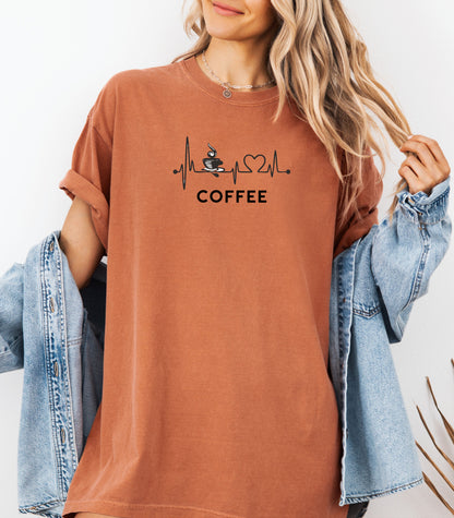 Graphic Yam t-shirt design featuring a heartbeat line that flows through a steaming coffee cup and forms a heart shape before it finishes.  A creative and stylish illustration that shows coffee is essential to life—perfect for caffeine lovers, baristas, and anyone whose heart beats for coffee.